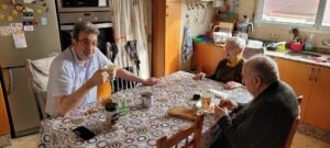 Una pareja de personas mayores y su hijo desayunando en su cocina.