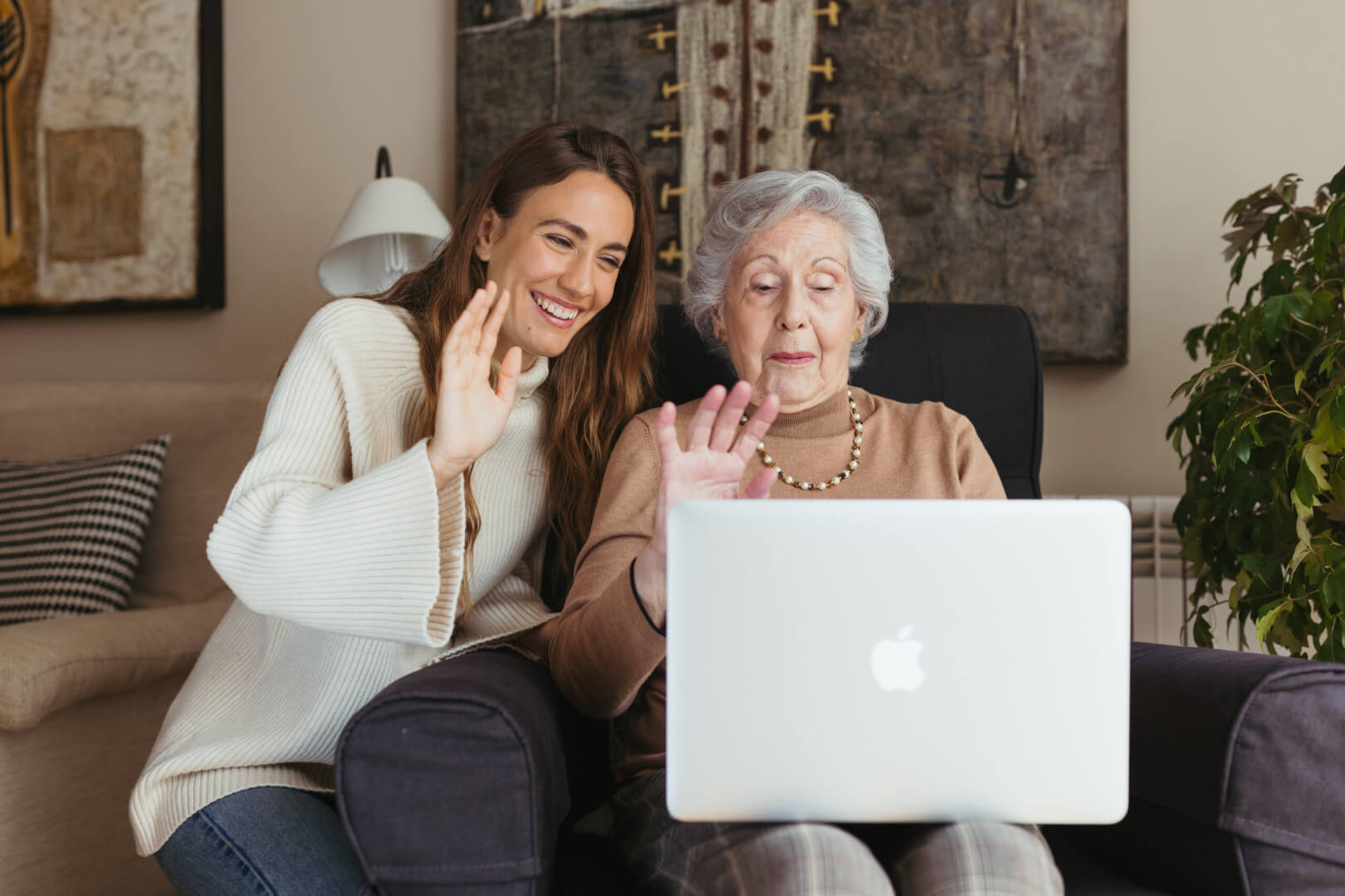 Una cuidadora enseña un programa en el ordenador portátil a una señora mayor.