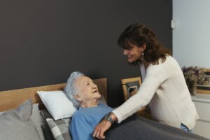Mujer mayor encamada con úlceras por presión es atendida por una cuidadora a domicilio