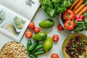 Verduras, cerezas, frutos secos y un libro de cocina sobre una mesa.