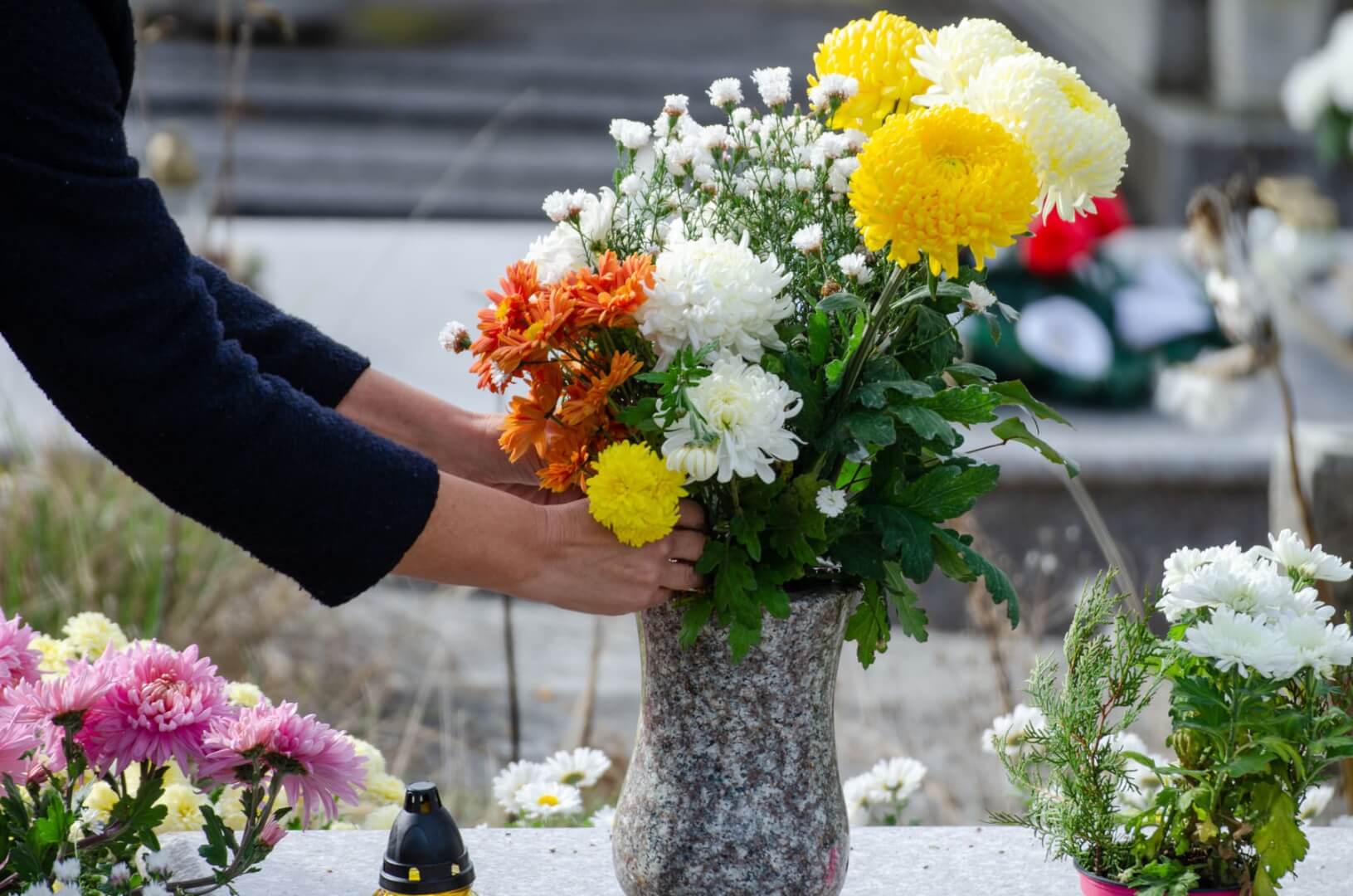 Una persona deposita unas flores sobre una tumba.
