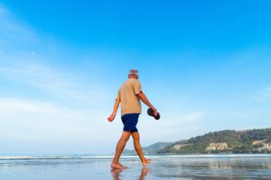 Hombre mayor caminando descalzo por la orilla de una playa
