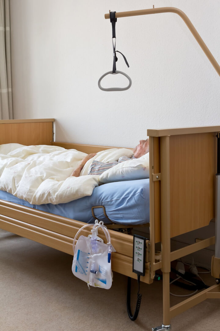 Una cama de una persona mayor con una grúa para desplazarse.