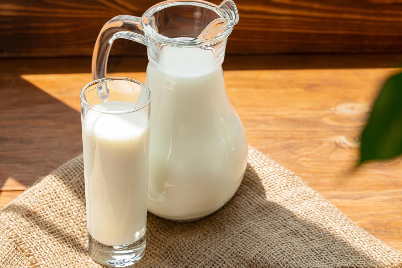 Una imagen de una jarra de leche y un vaso de leche en una mesa.
