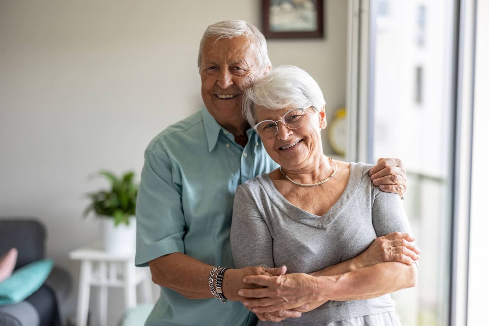 Una pareja de ancianos posan cariñosamente mientras ríen a cámara.