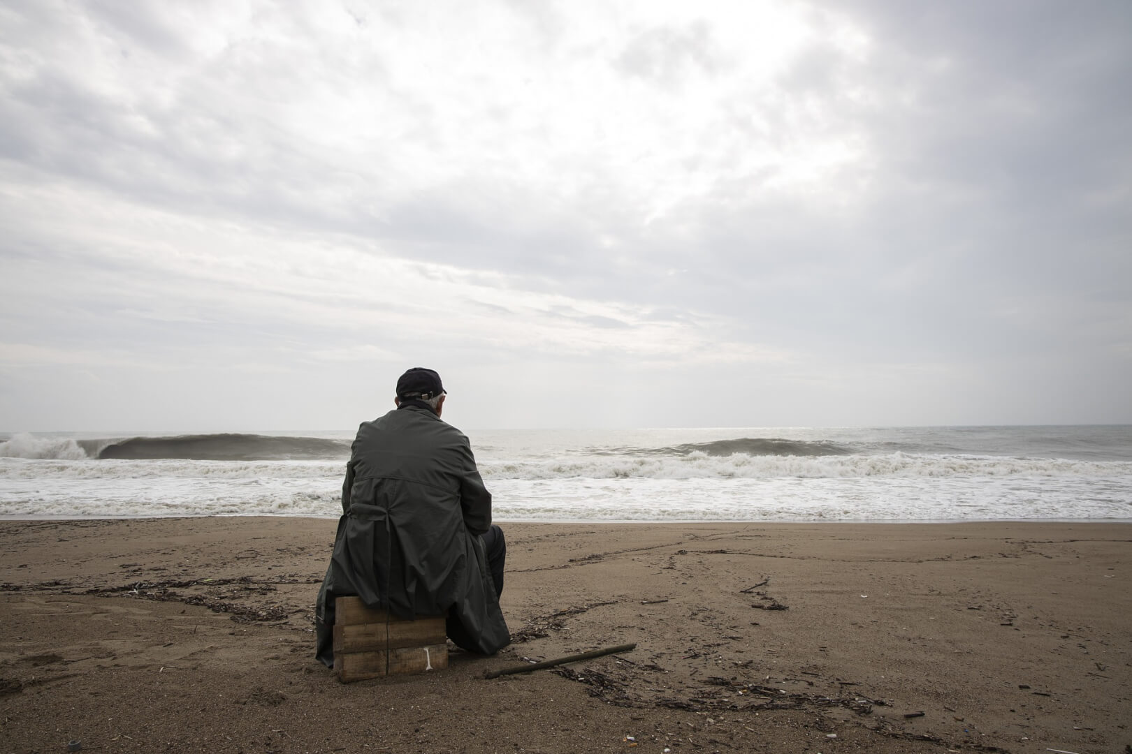 Un hombre sentado en la arena de la playa.