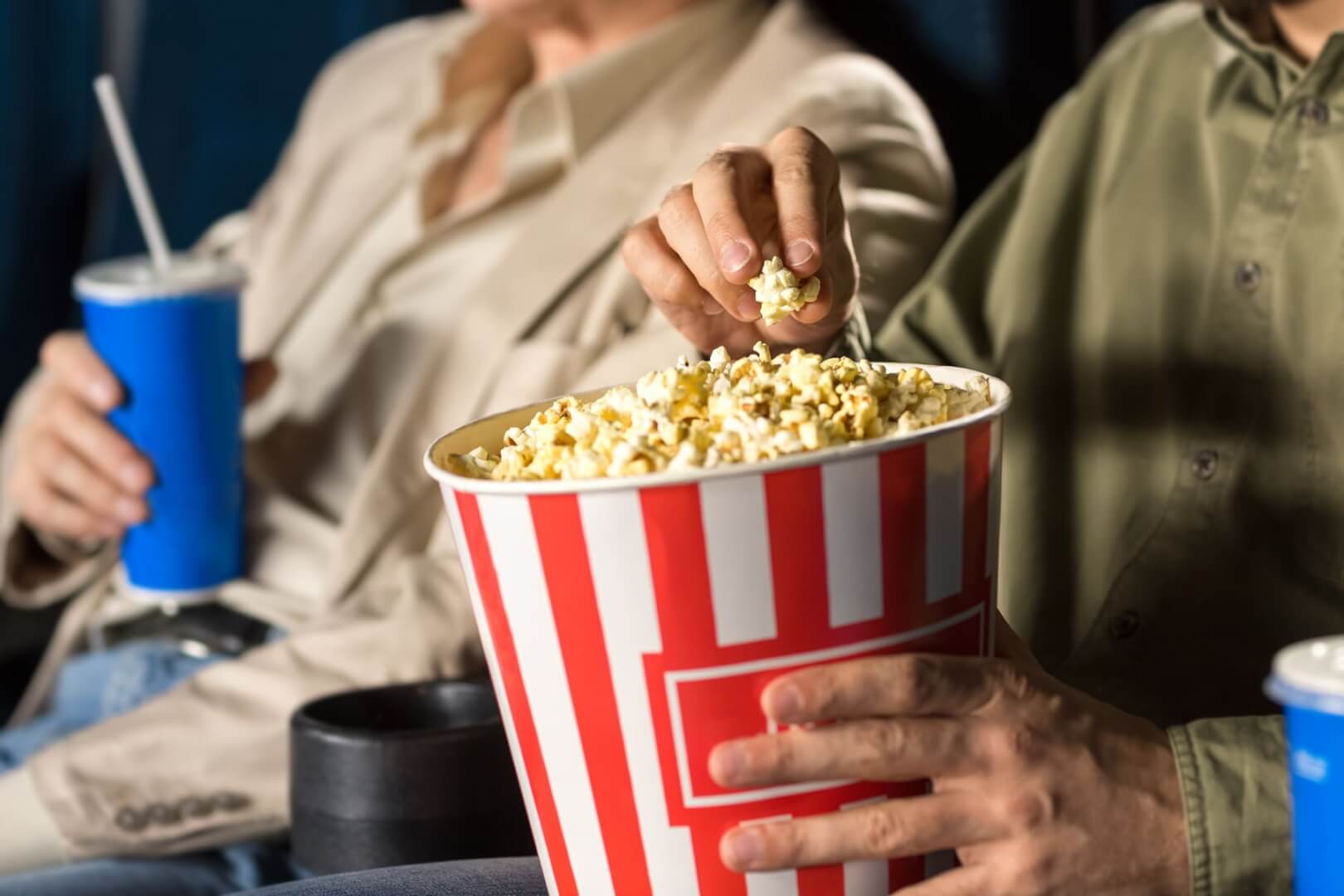 Dos ancianos comen palomitas y beben refrescos en el cine.
