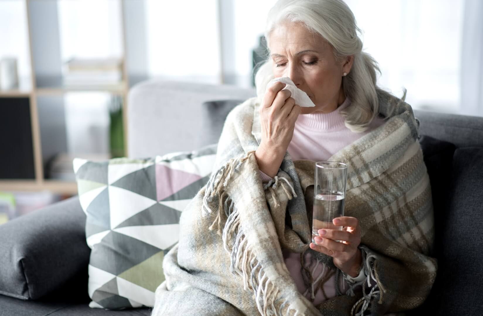 Una anciana se suena con un pañuelo en claro gesto de incorporar un constipado. 