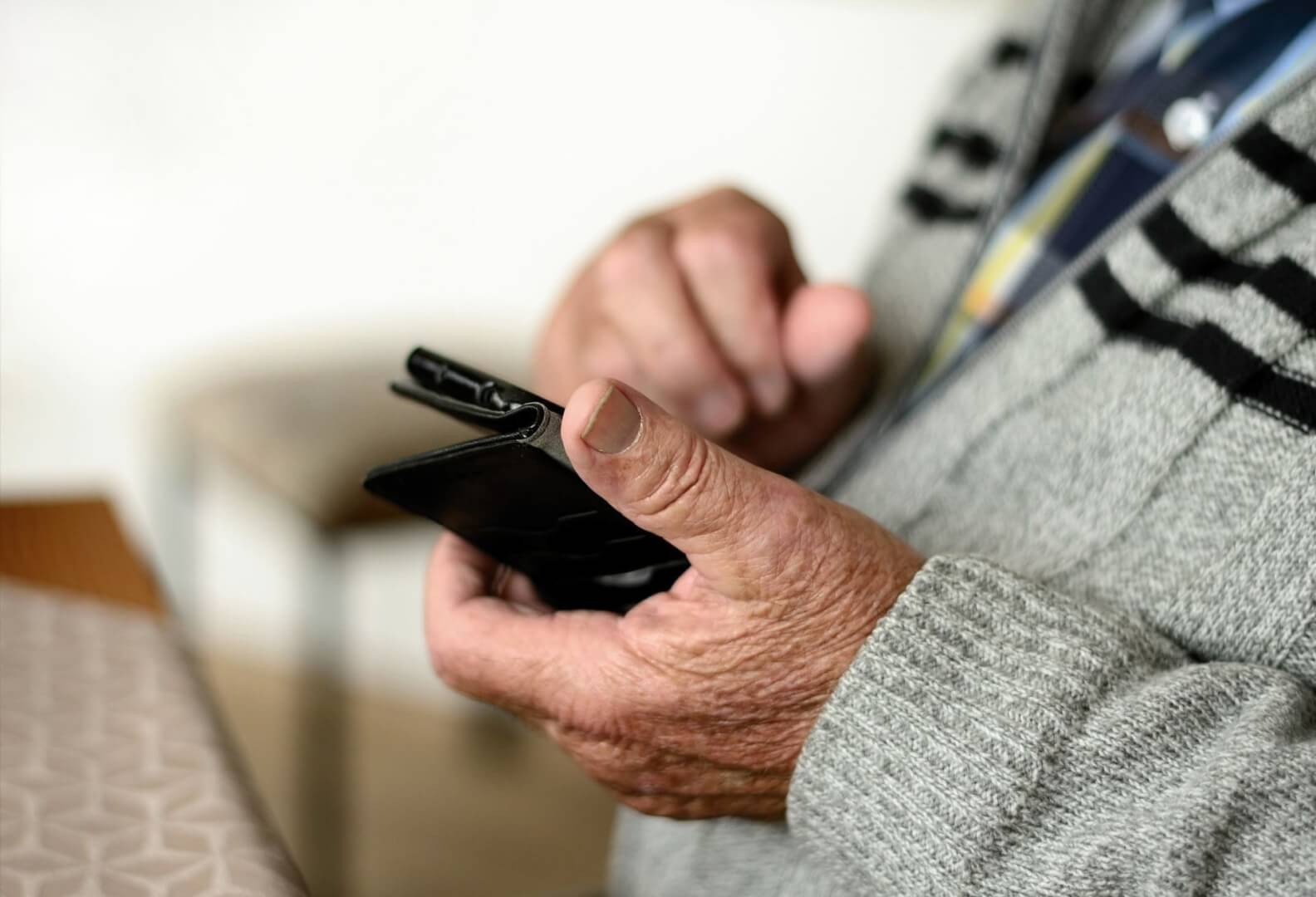 Un plano corto de las manos de un anciano con el smartphone.