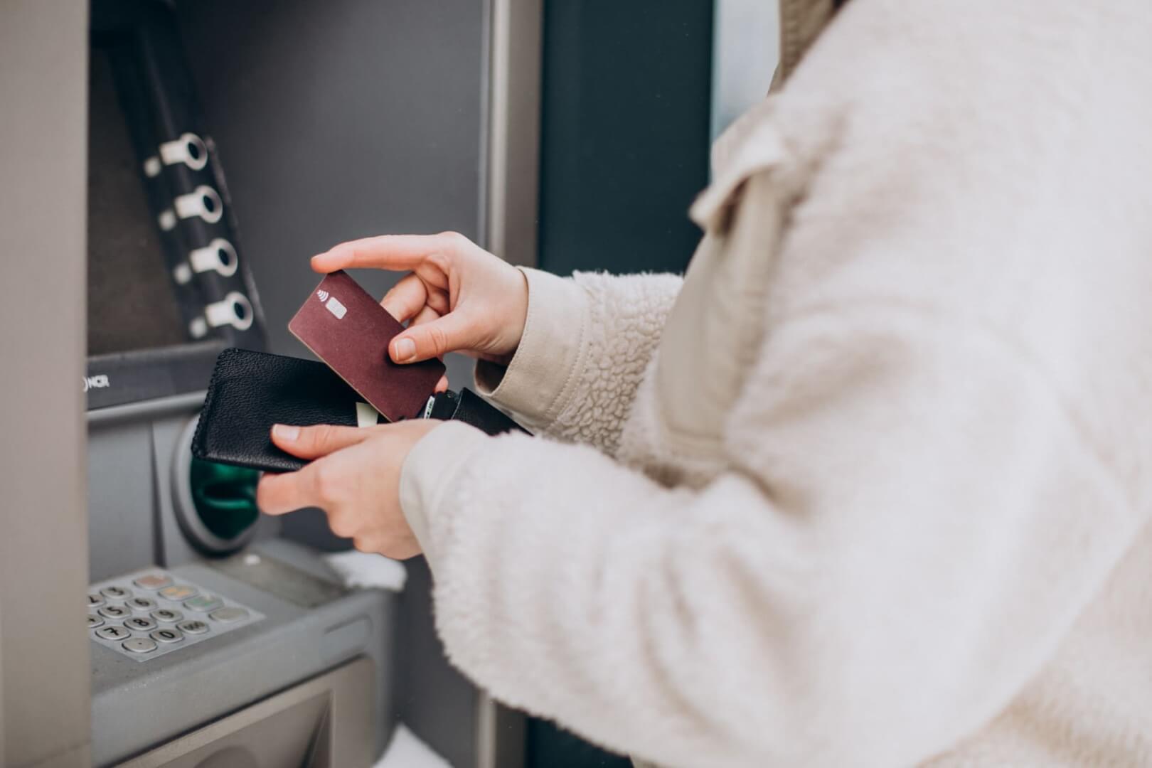 Una señora mayor introduce una tarjeta de crédito en un cajero automático. 