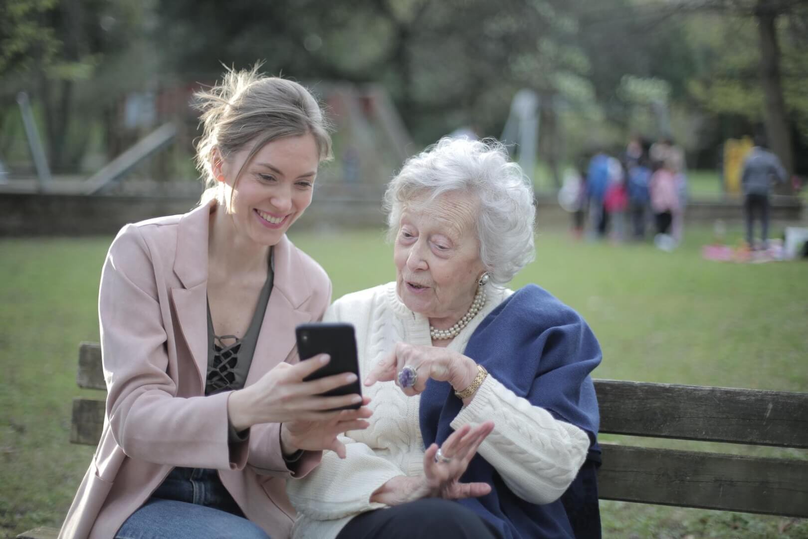 Una cuidadora enseña algo en el smartphone a una anciana. 