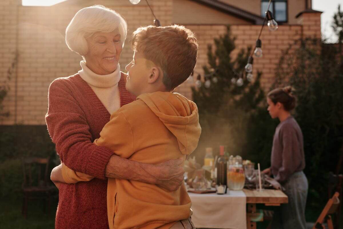 Una abuela abrazando a su nieto en el patio de su casa
