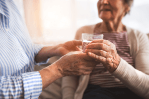 Anciano hidratando a una abuela con un vaso de agua