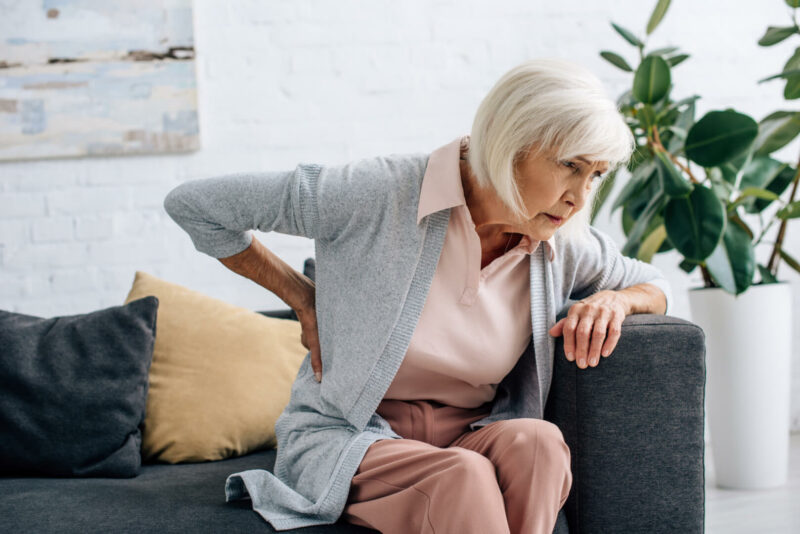 Mujer anciana con dolor de espalda causado por la osteoporosis 