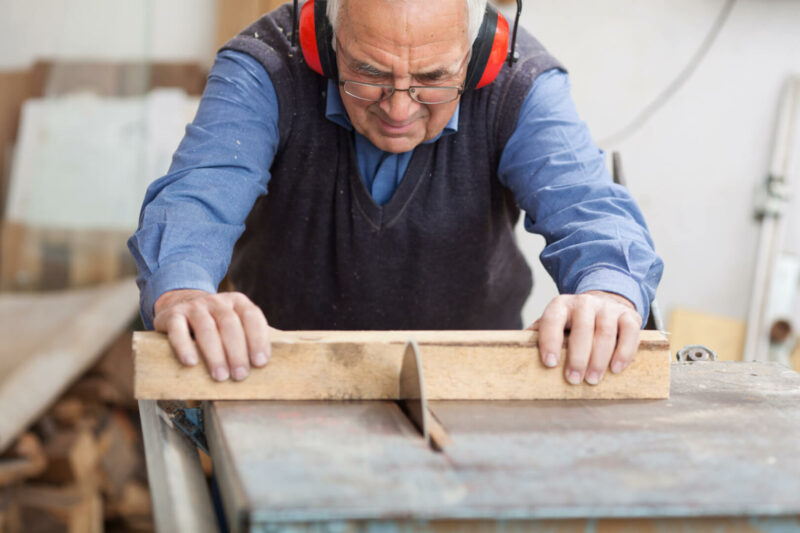 Un anciano asiste a una clase de carpintería mientras se encuentra concentrado.