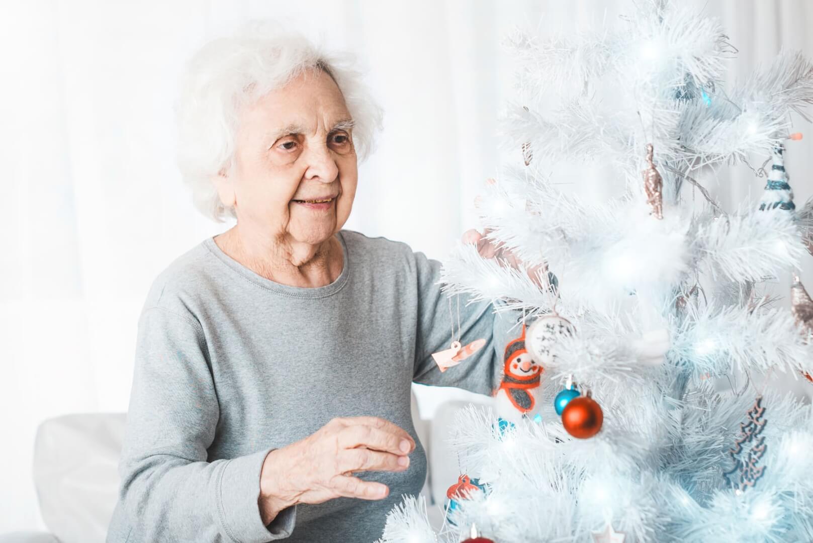 Una anciana decora su árbol de Navidad.