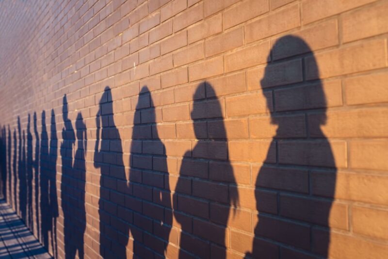 Unas sombras de personas en la pared esperando en la cola del paro.