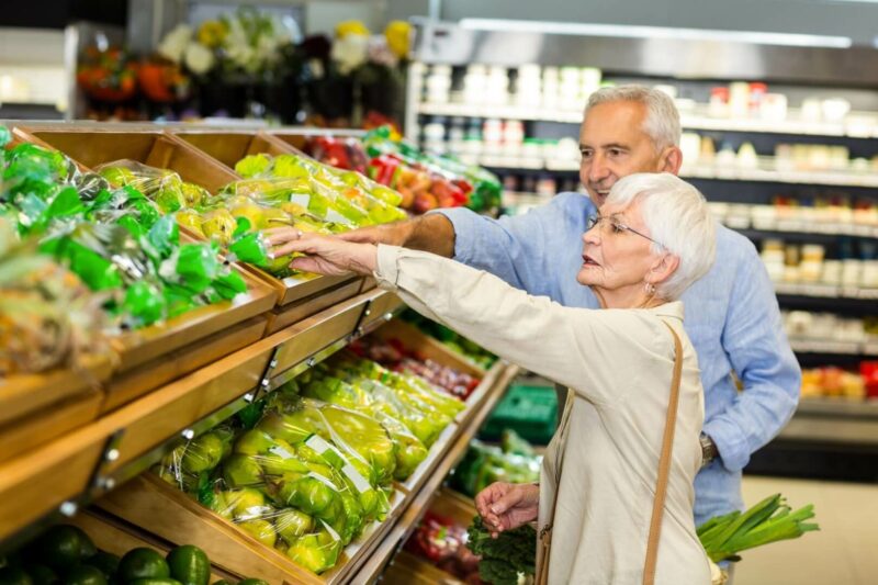 Una pareja de ancianos escogen en la frutería de un supermercado la fruta que van a comprar.