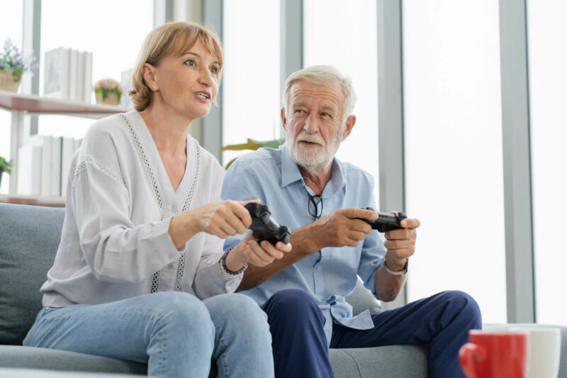Una mujer adulta y su padre anciano juegan a la consola