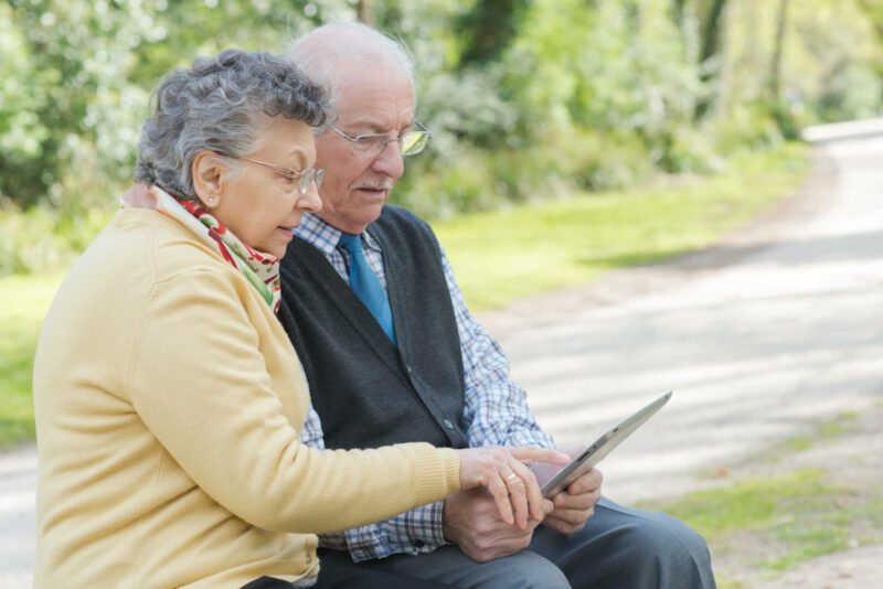 Una pareja de ancianos hace una videollamada con algún familiar mientras se encuentran en un parque. 