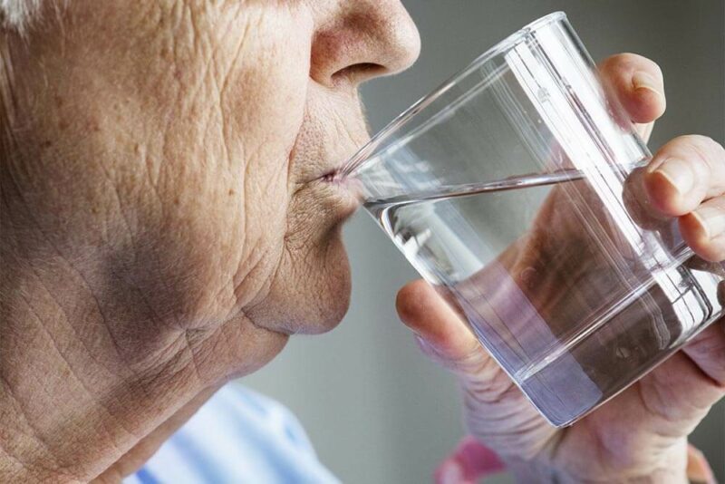 Anciano bebiendo agua.