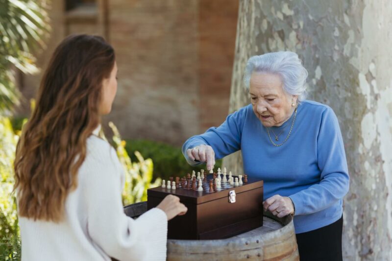 Una cuidadora juega al ajedrez con una anciana.