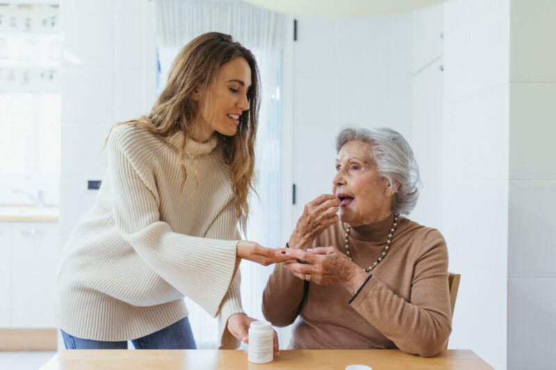 Una cuidadora administra la medicación a una señora mayor. 
