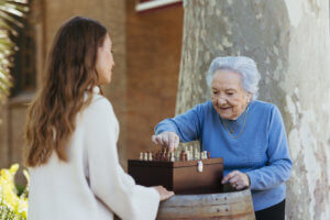 Abuela y cuidadora jugando al ajedrez en el parque ribalta