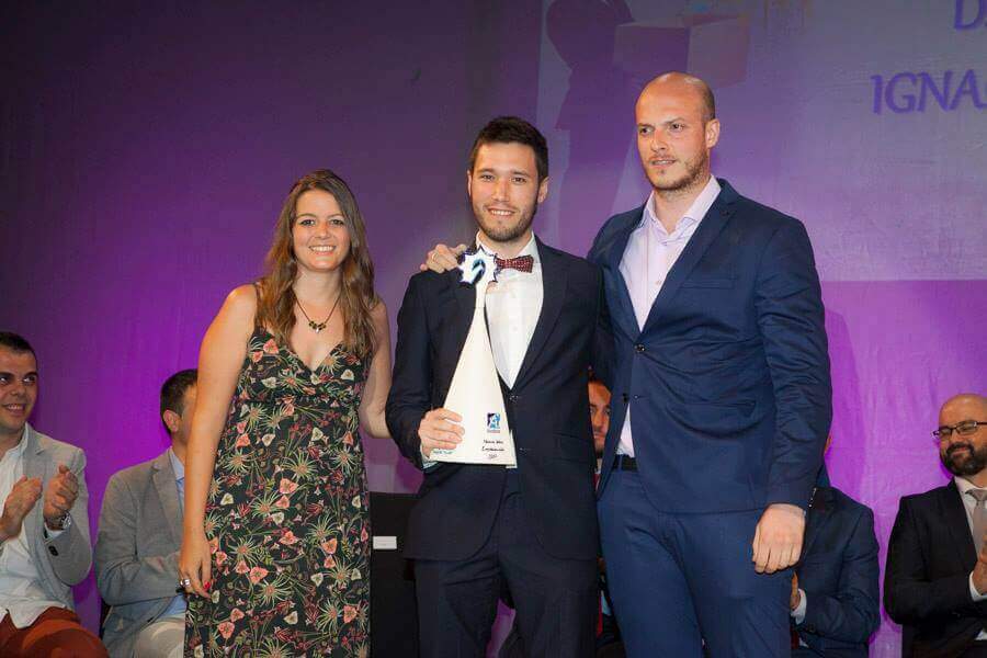 Daniel Ibiza CEO de Aiudo posa sosteniendo un premio junto un hombre y una mujer