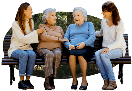 Dos cuidadoras y dos mujeres mayores sentadas en el banco de un parque de Valencia.