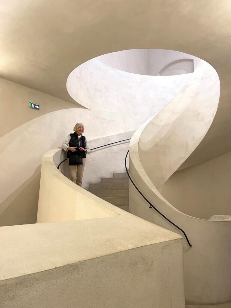 Una anciana en una escalera en forma de caracol de un edificio. 