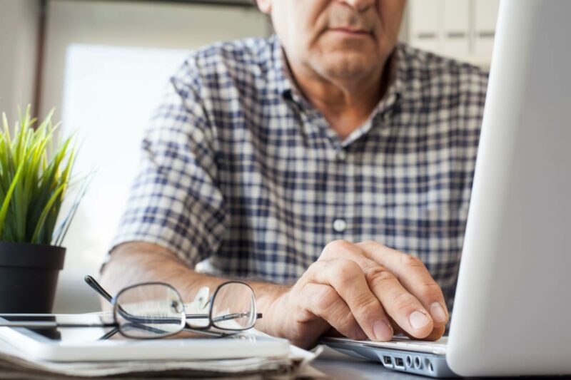 Un pensionista mira su ordenador portátil. 