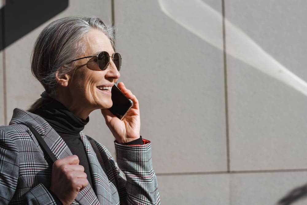 Una anciana habla por teléfono con unas gafas de sol puestas.
