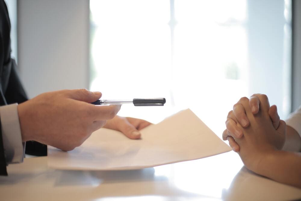 Un plano detalle de las manos de dos personas firmando un contrato. 