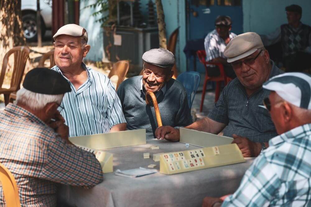 Un grupo de señores mayores jugando a un juego de mesa en la calle. 