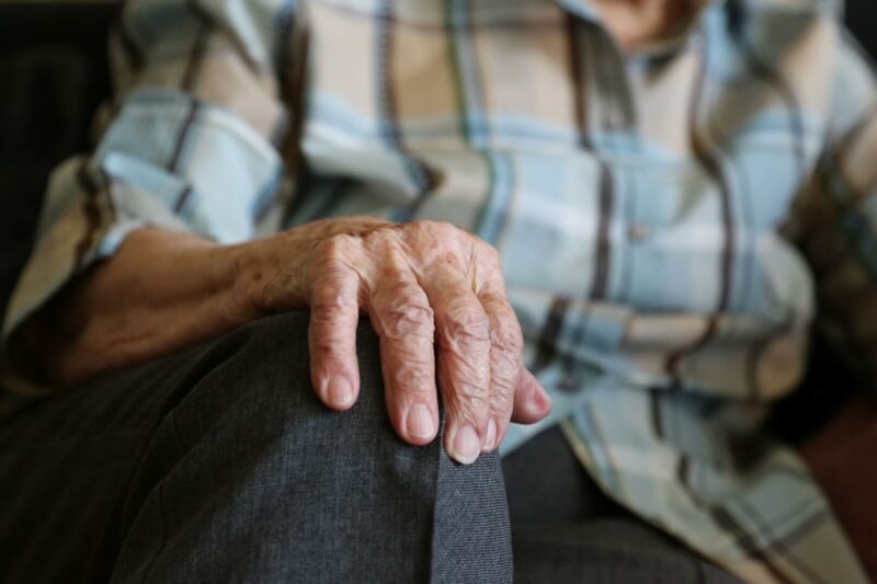 Una persona mayor sentada en un plano corto de su mano