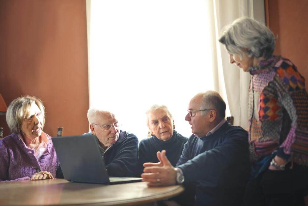 Un grupo de personas mayores discuten en una mesa. 