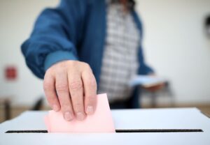 Plano corto de una persona introduciendo una papeleta en la urna electoral