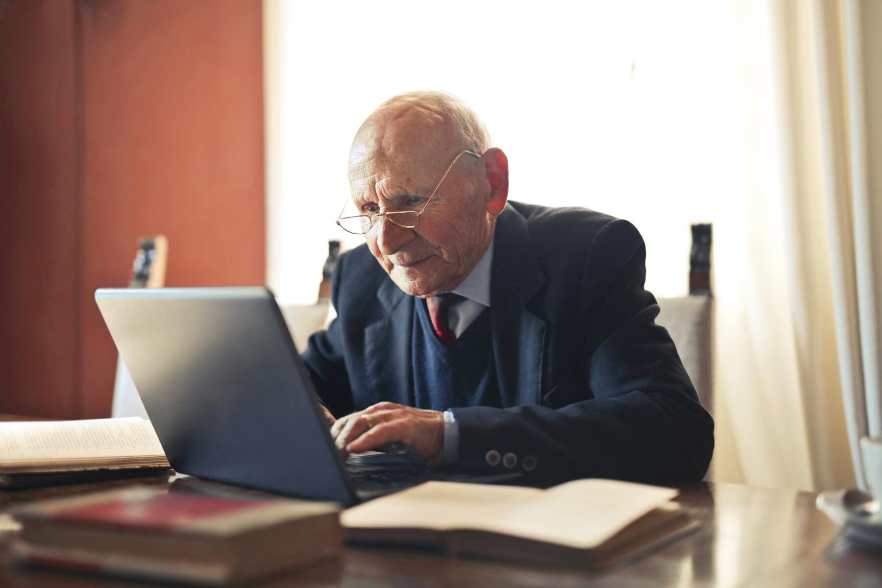 Un anciano observa en el portátil de su ordenador para realizar un trámite. 
