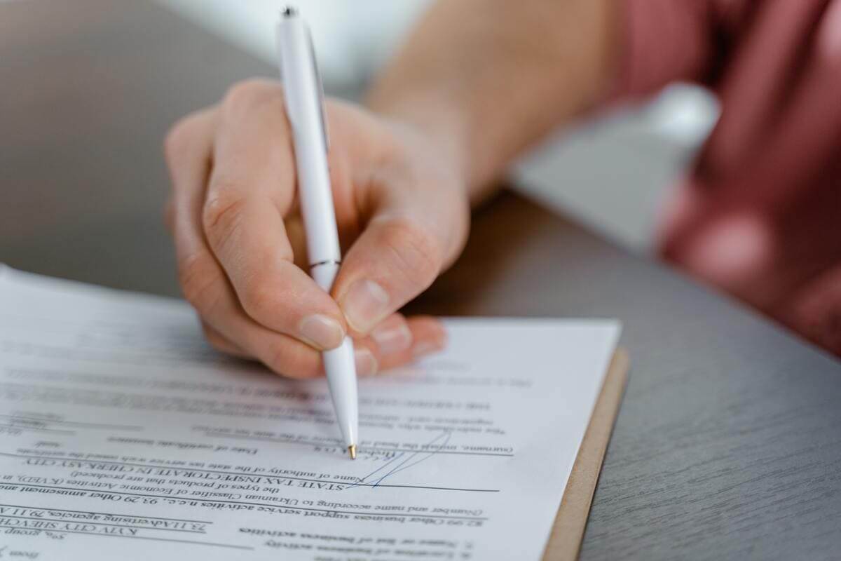 Una persona firmando un contrato en un plano detalle del mismo. 