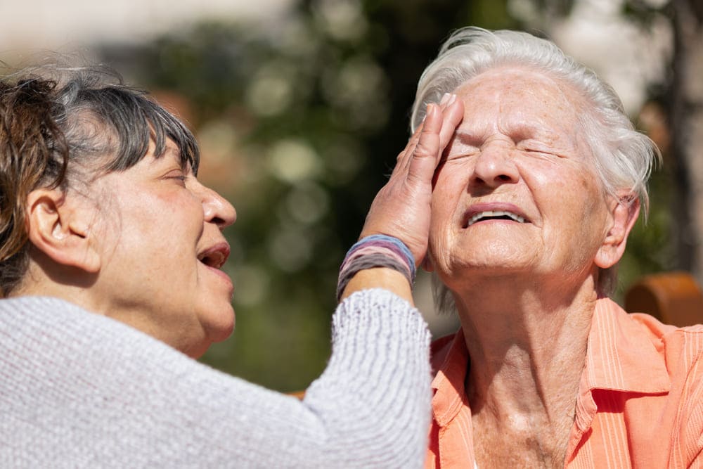 Una anciana pone crema solar en la cara a otra anciana. 