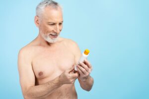 Un anciano mira con asombro una crema solar.