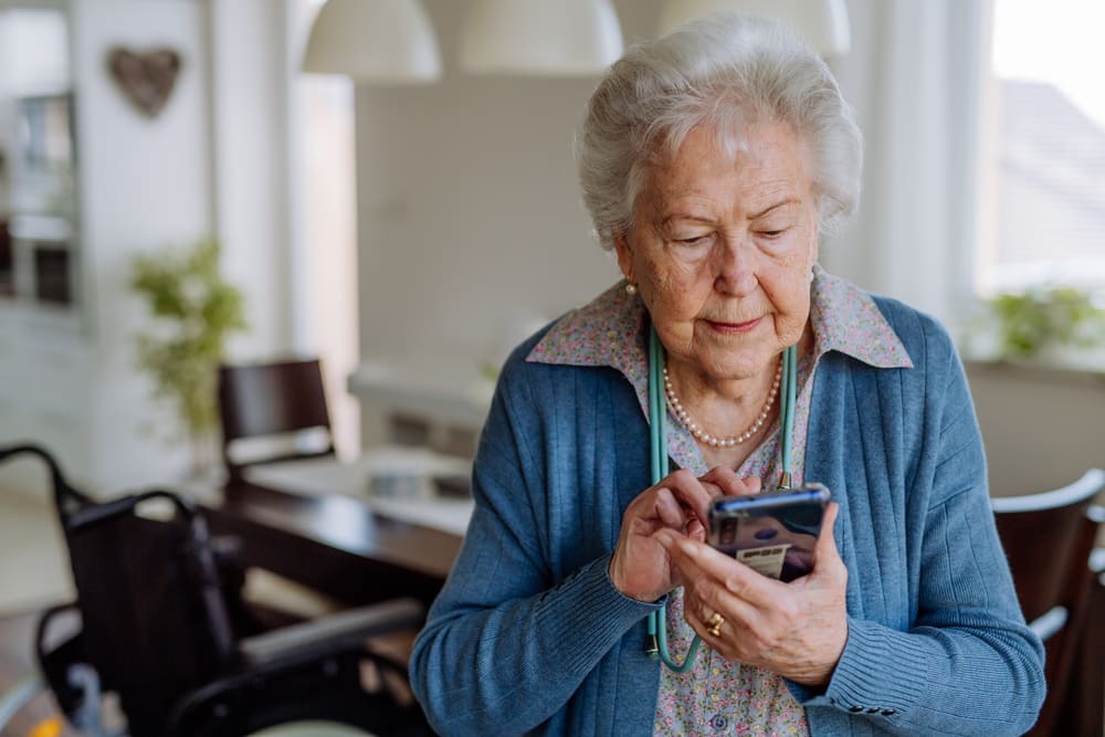 Una mujer mayor con un móvil en la mano.