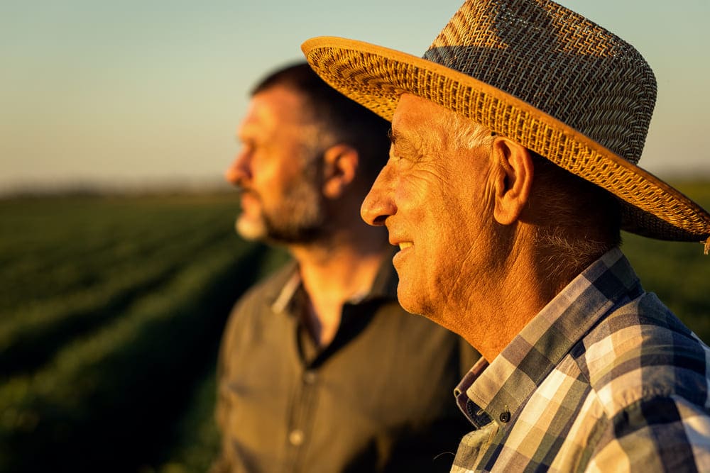 Un hombre mayor con sombrero mira al horizonte junto a su hijo. 
