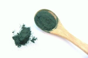 Una cuchara de madera con espirulina en polvo