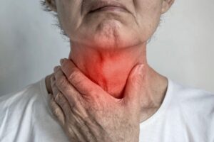 Una mujer mayor se toca la garganta ante un posible síntoma de atragantamiento.