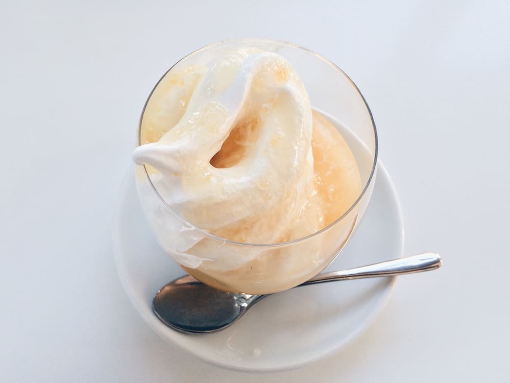 Un yogur helado de vainilla listo para servir en un vaso, una taza y una cuchara. 