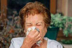Una mujer mayor se suena la nariz con un pañuelo.