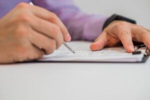Un plano detalle de unas manos de una persona mayores firmando sobre un documento.