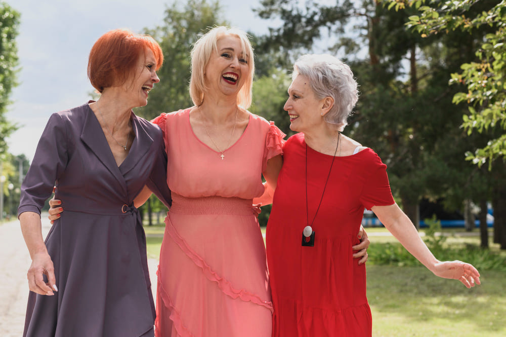 Tres mujeres mayores riendo, caminando bajo el sol
